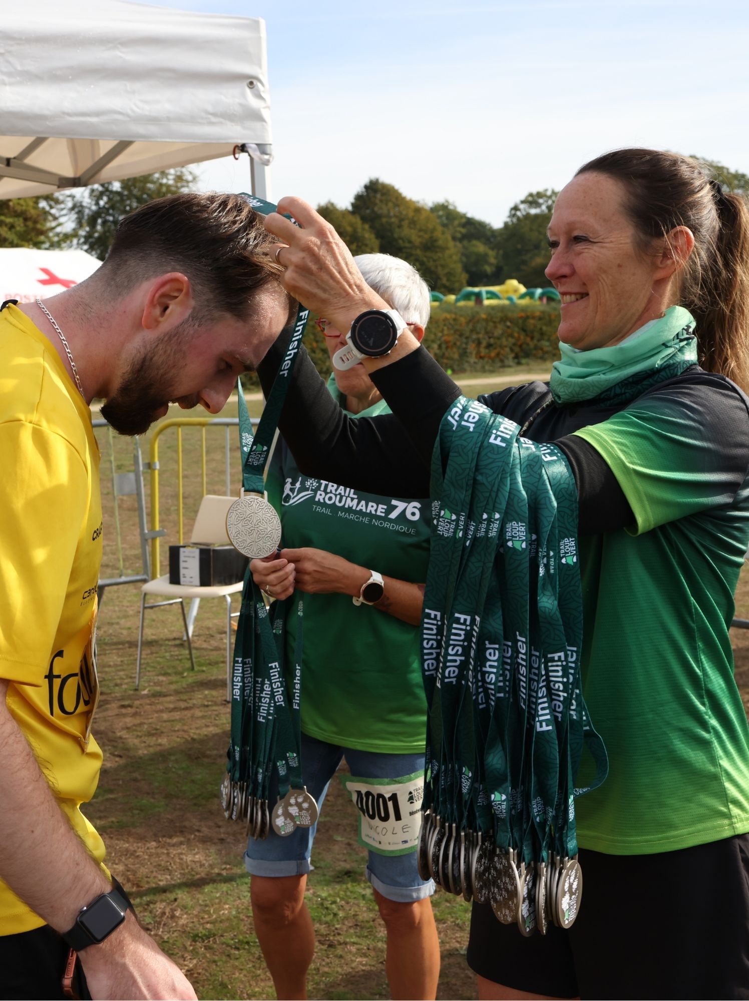 Bénévole accrochant la médaille finisher au cou d'un coureur